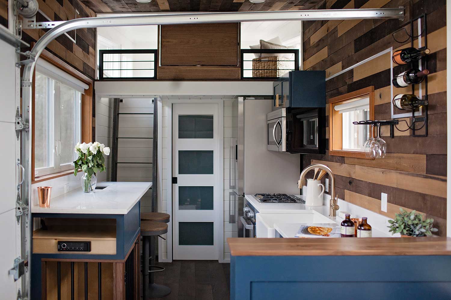 Interior of a tiny home showing garage doors kitchen and loft