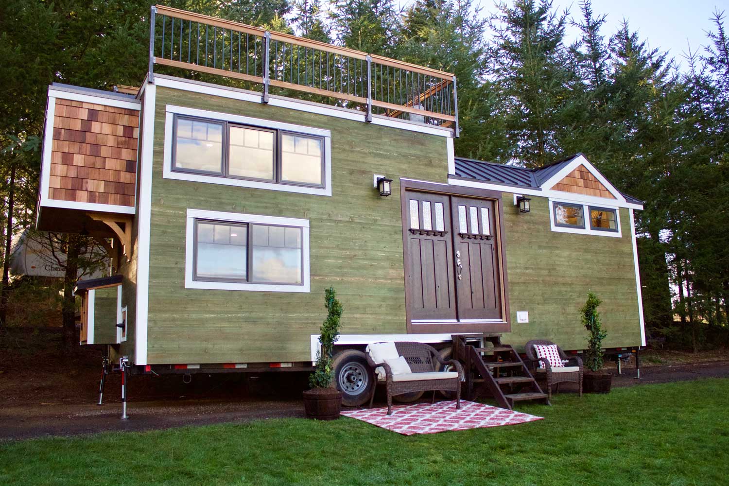Outside shot of a Craftsman tiny home with roof deck, double doors and more