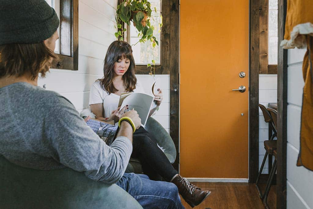 Man and woman read magaiznes in the sitting area of their Tiny Heirloom Genesis custom tiny house