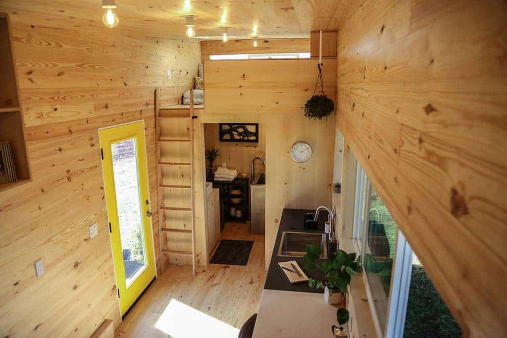 Interior of odern Shou Sugi Ban custom tiny home showing kitchen and ladder to loft