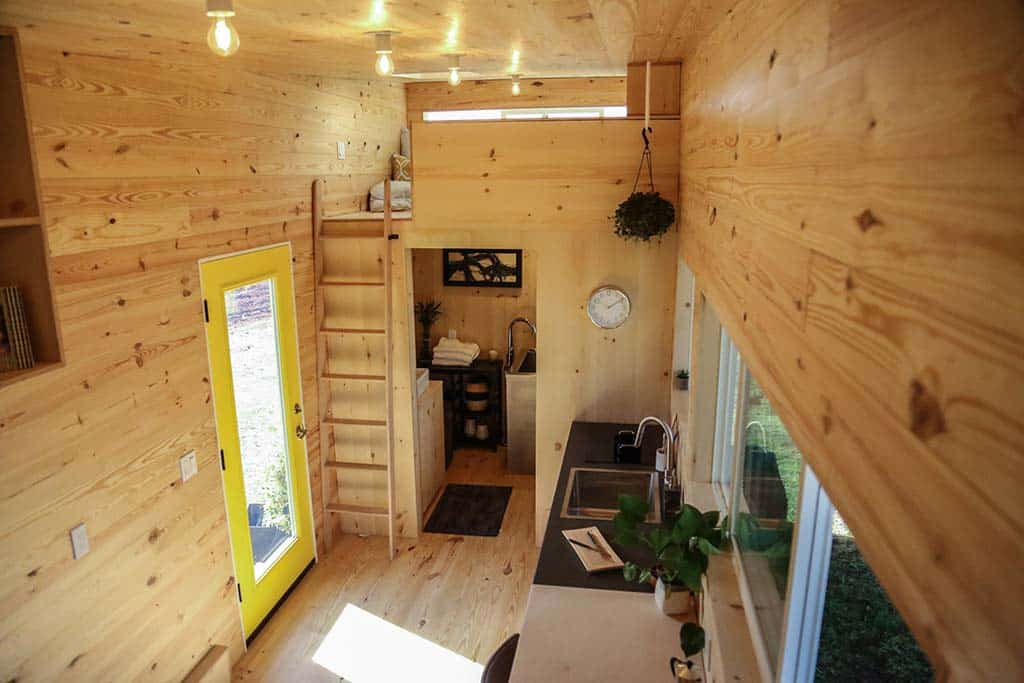 Interior of odern Shou Sugi Ban custom tiny home showing kitchen and ladder to loft