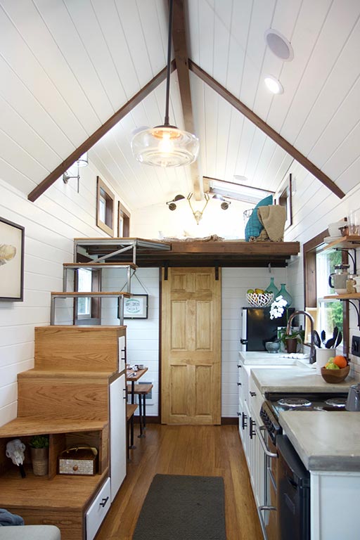 Interior of the NW Natural custom tiny house showing stairs to loft and the kitchen