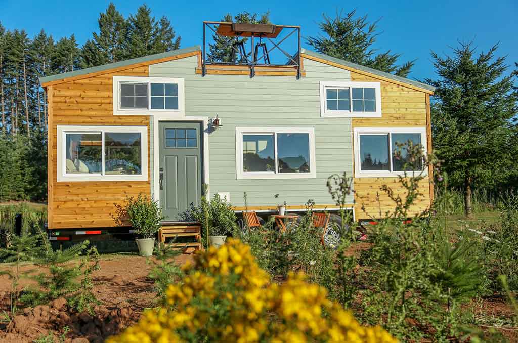 Outside view of the Rustic Farmhouse custom tiny home set in a garden