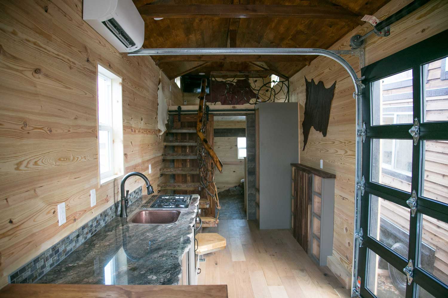 Interior of the Rustic Mountaineer custom tiny house with kitchen and stairs to loft