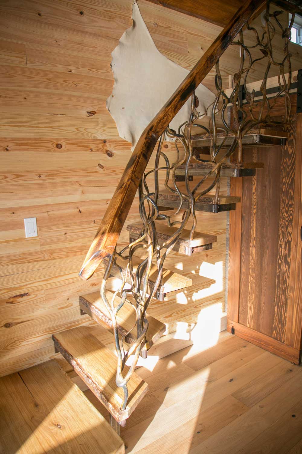 Custom wood railings on stairs in the Rustic Mountaineer custom tiny house