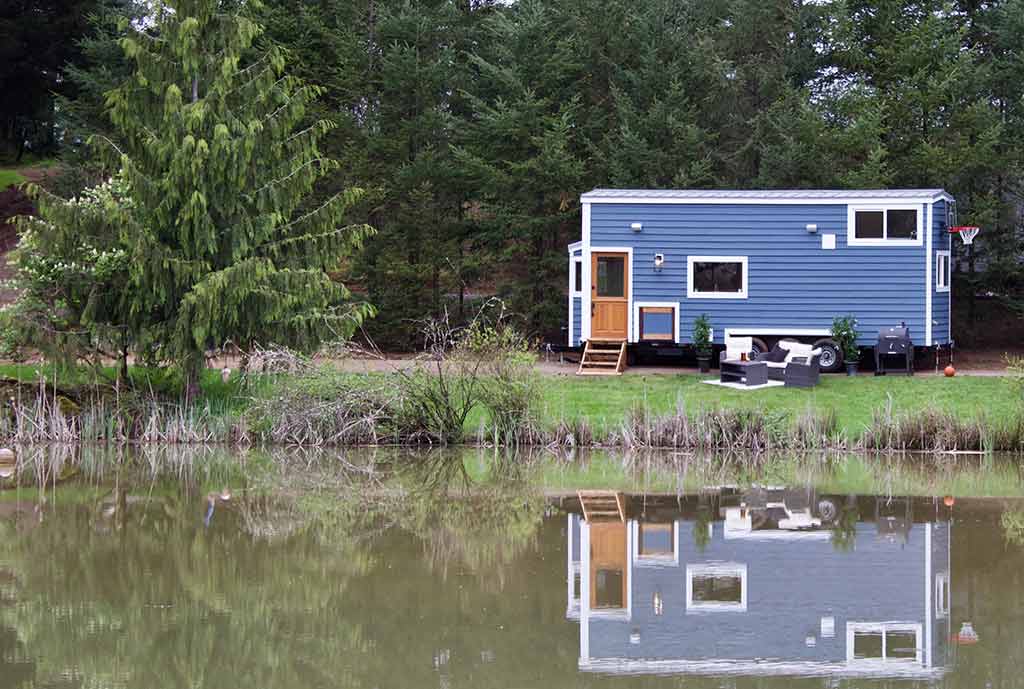 The Tailgating Farmhouse custom tiny home outside shot reflecting in a lake
