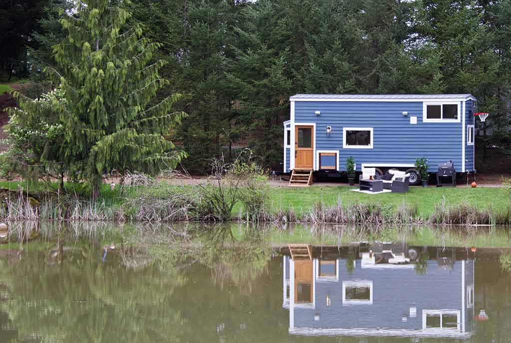 The Tailgating Farmhouse custom tiny home outside shot reflecting in a lake