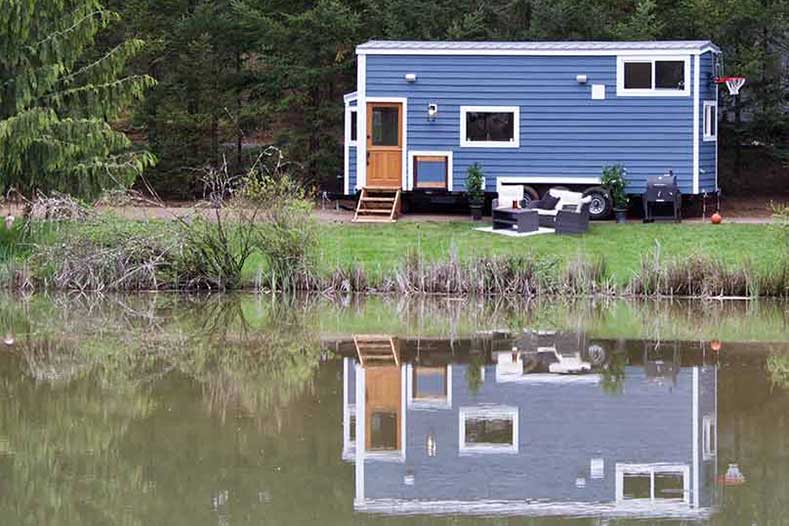 The Tailgating Farmhouse custom tiny home reflecting in a lake