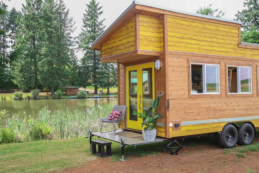 Porch on the Beachy Bohemian custom tiny home with lake and trees in the background