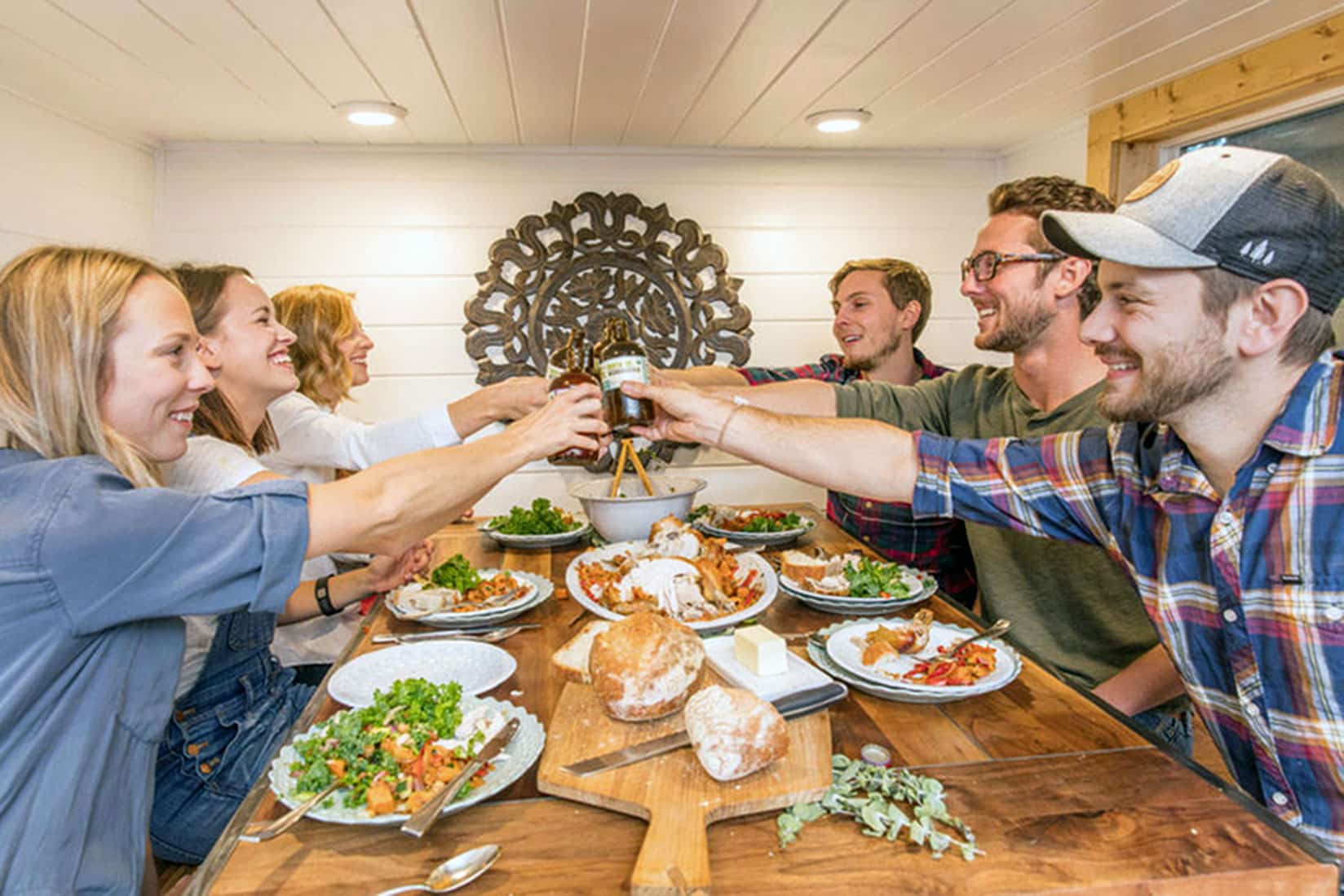 Tiny Heirloom team cheers over dinner table in a tiny home they built