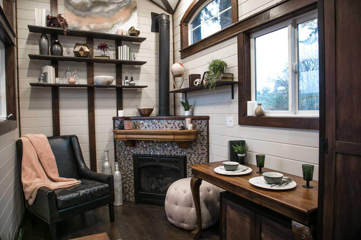 Cozy living room featuring a fireplace of the Tudor custom tiny home built by TIny Heirloom