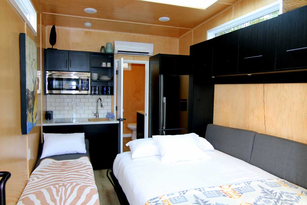 Interior of an example of the expanse tiny houses for sale by Tiny Heirloom featuring two beds and a kitchen