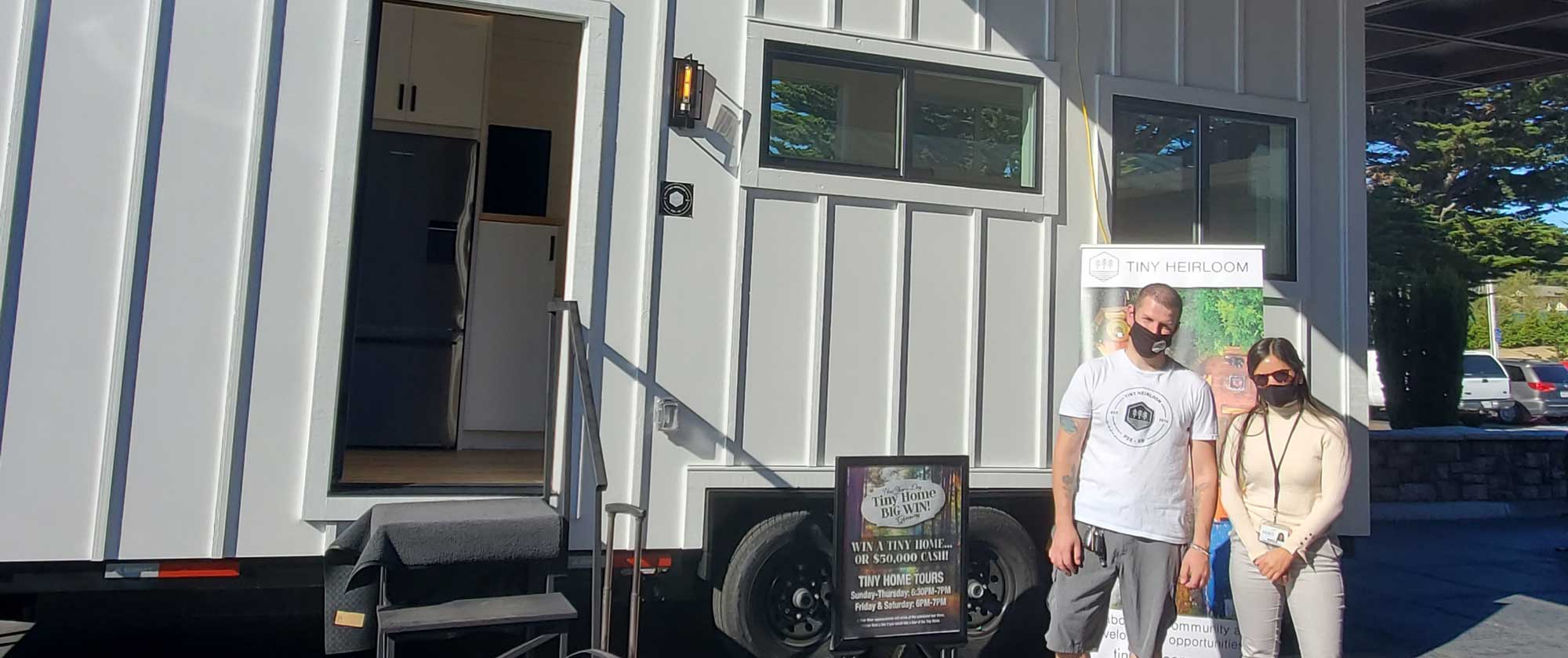 Kayla and her husband pose in front of their Casino Tiny Home they bought from Tiny Heirloom