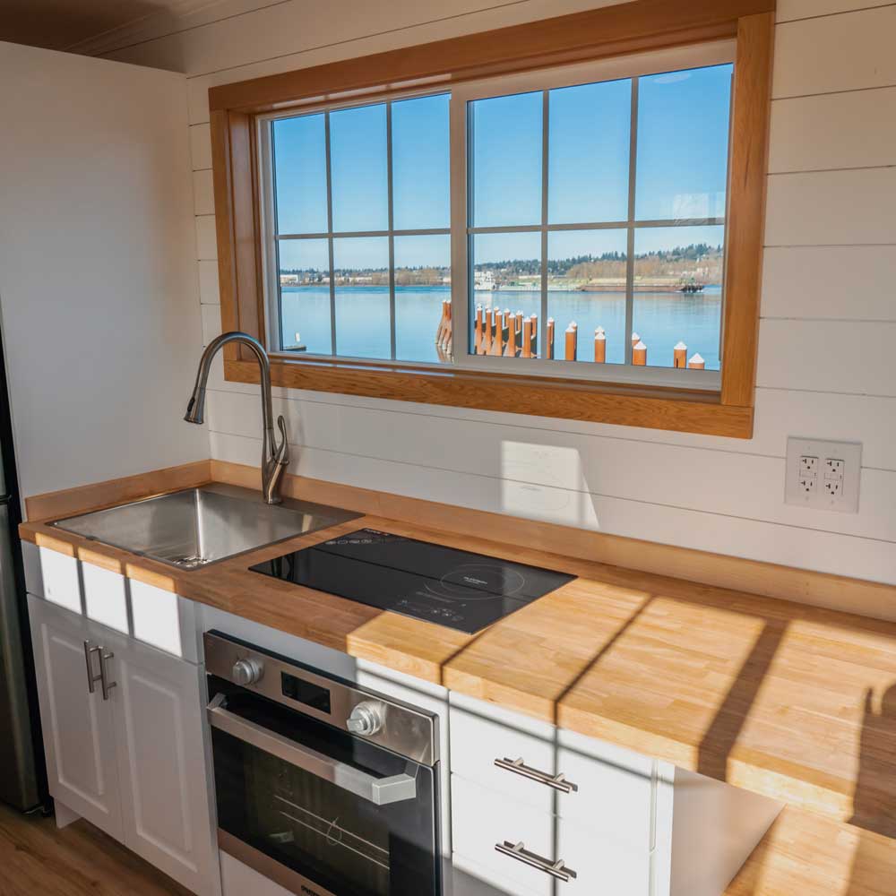 Interior of Legacy tiny home showing kitchen and a lake out the window