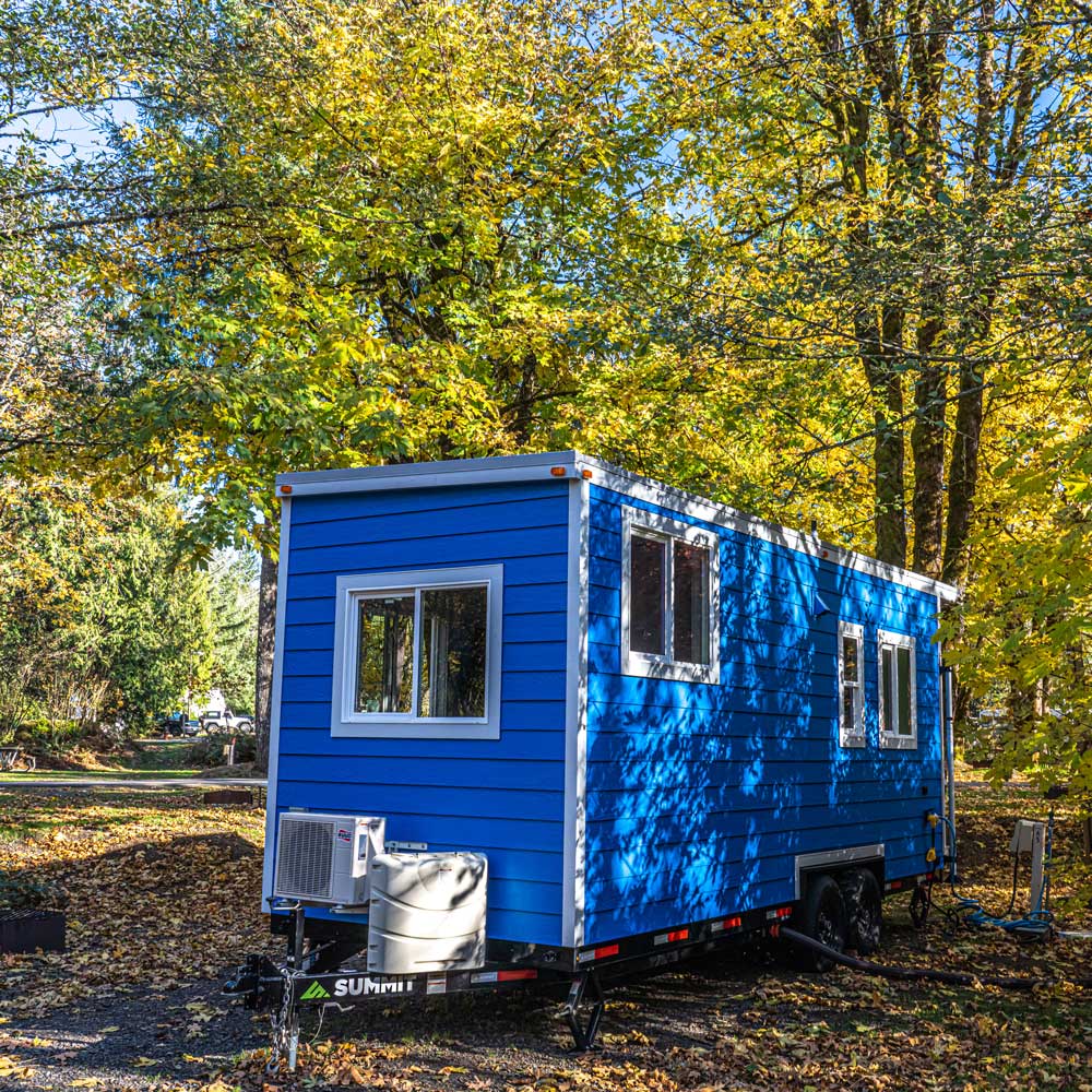 The True Blue custom tiny home set in a leafy forest