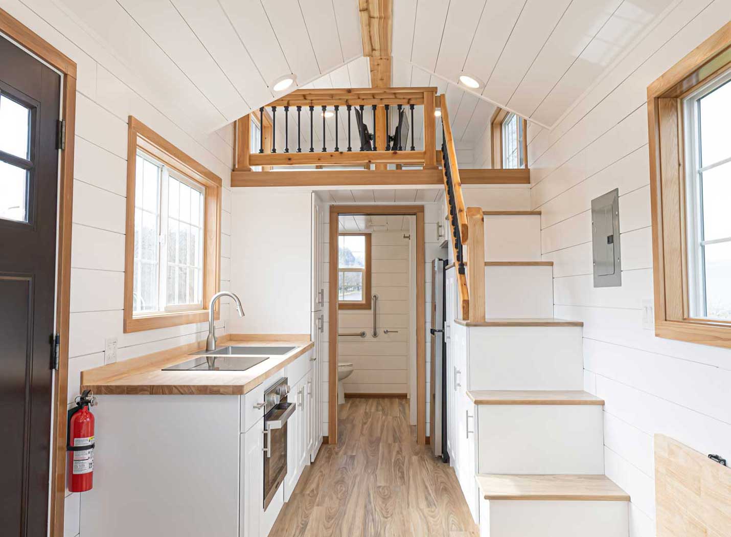 Heritage tiny home model in the craftsman style, for sale as part of Tiny Heirloom's Signature Series line. Interior shown with kichen and stairs leading to loft