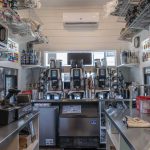 Interior of a custom commercial tiny home set up as a coffee stand with espresso machines, counter space, flavored syrups and more