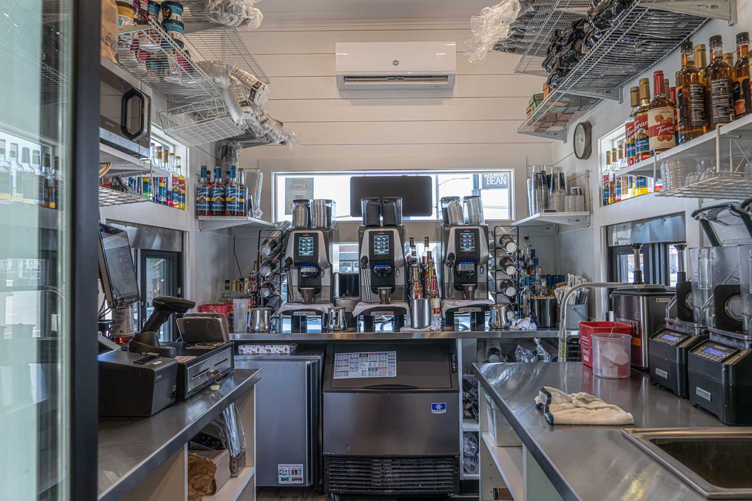 Interior of a custom commercial tiny home set up as a coffee stand with espresso machines, counter space, flavored syrups and more
