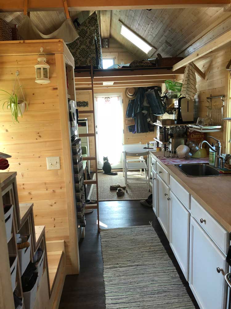 Interior of the Contemporary Cottage custom tiny home with kitchen and stairs and ladder to lofts